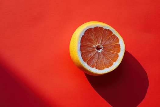 Fresh orange half with shadow on vibrant red background, concept of health and wellness in beauty and nutrition industry