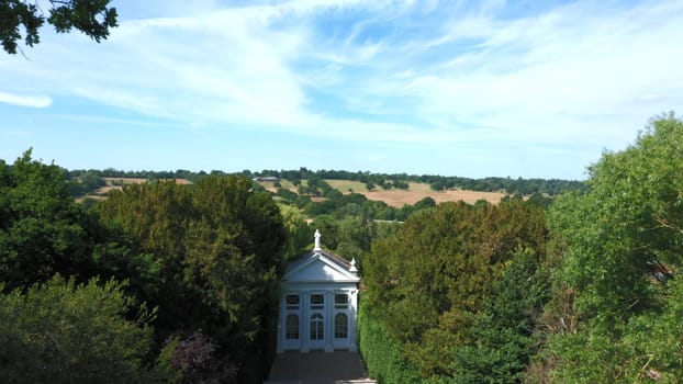 Aerial top down view from the drone onto the narrow passageway leading to a small chapel. Chapel located in a big green open area of fields near Rosary Manor, Mill Hill, North West London, London, UK.