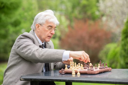 Elderly Caucasian man playing chess outdoors