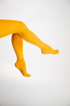 Female legs in ocher tights on a white background. Vertical photo