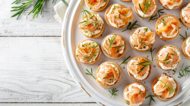Plate of smoked salmon canapes with herbs on a white wooden table
