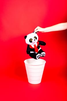 Woman putting the broken toys in waste bin on red background, copy space