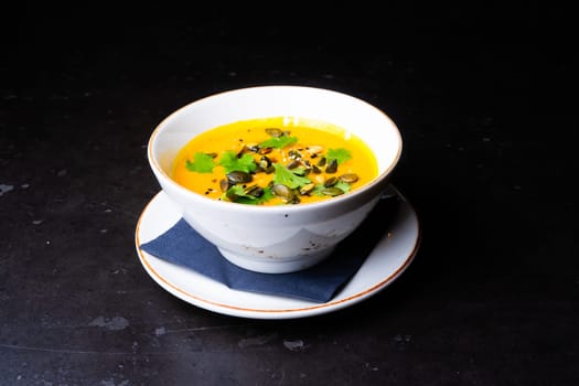 Pumpkin cream soup with parsley on a gray stone and wooden background. Top view, copy space