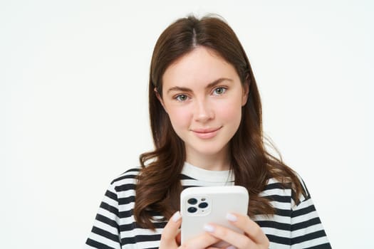 Portrait of woman checking her messages on mobile phone, looking at smartphone screen.