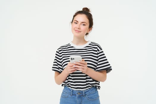 Image of young smiling woman, holding mobile phone, using smartphone application, isolated over white background.