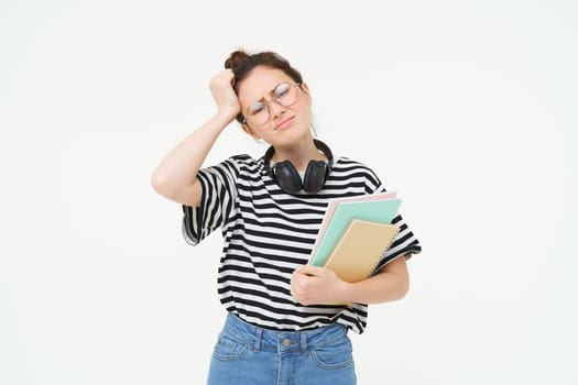 Image of upset young woman, student in glasses complains at difficult task at university, holding notebooks, forgot to do something, white background.