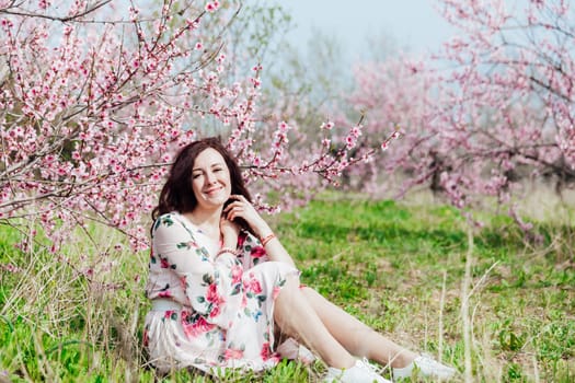 woman sitting in garden of blooming pink trees nature park spring