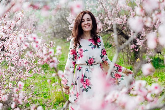 woman stands in a garden of flowering pink trees nature park spring