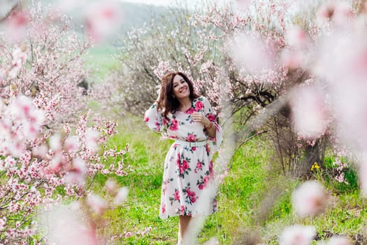 woman stands in a garden of flowering pink trees nature park spring