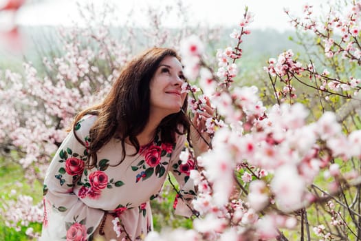 a woman sniffs pink flowering trees in peach garden nature spring