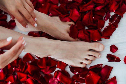 legs and hands of woman in red rose petals