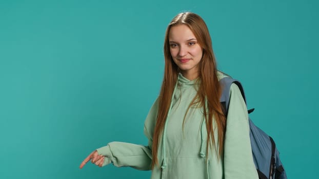 Portrait of cheerful person pointing finger towards empty space, doing advertising. Happy lady doing presentation, showing copy text, isolated over studio background, camera A