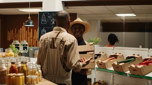 Small business owner receiving new produce stock from contractor, bringing freshly harvested natural products from local farm. African american man supplying organic grocery store. Camera 1.