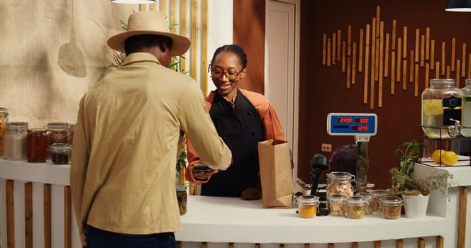 Vegan client buying ethically sourced fruits and vegetables at pos, shopping for locally grown additives free food in market. African american vendor scanning all products for customer. Camera 2.