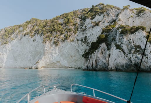 Beautiful panoramic view of a green mountain island in the blue sea with the bow of a boat on a sunny summer day, close-up side view.