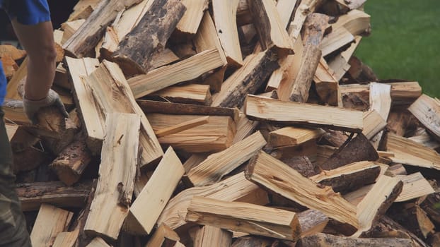 A man works with an ax in his yard, processing firewood for the winter season, burning firewood, heating firewood in the countryside