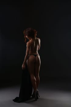 Erotica. Rear view of slender red-haired woman in thong