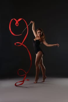 Photo of sexy artistic gymnast dancing with red ribbon
