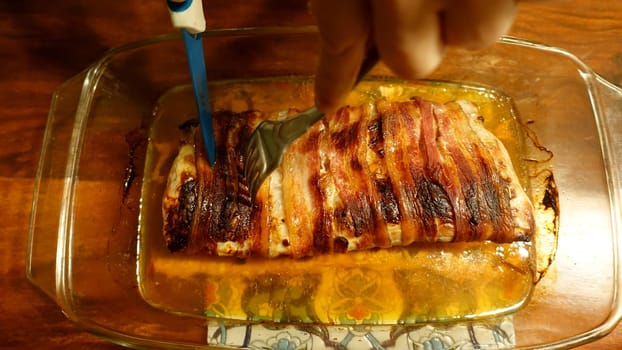 A slice of pork tenderloin fresh from the oven wrapped in strips of bacon.