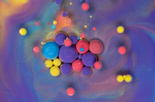A close-up photograph showcasing a mesmerizing array of colorful bubbles suspended in a liquid medium, creating a stunning abstract composition. The bubbles exhibit a vibrant spectrum of hues.
