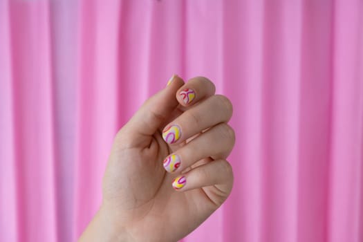 Pastel softness colorful manicured nails on pink background. Woman showing her new summer manicure in colors of pastel palette. Simplicity decor fresh spring vibes earth-colored neutral tones design