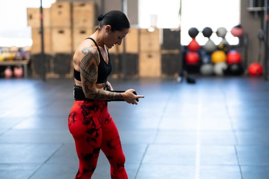 Strong woman attaching a belt to prevent injuries while weightlifting in a cross training gym