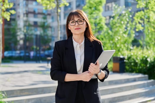 Portrait of business mature confident successful woman with laptop outdoor, educational office building background. Office employee school teacher insurance banking law firm real estate agent