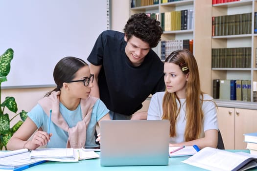 Group of high school students are studying in library class, classmates are laughing talking discussing together, team study project, preparing for tests and exams. Education adolescence communication