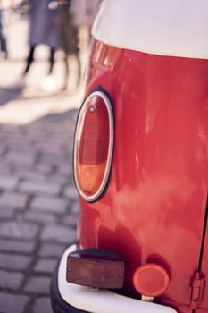 Close-up of a vintage car's tail light parked on a cobbled street, highlighting its classic aesthetic.