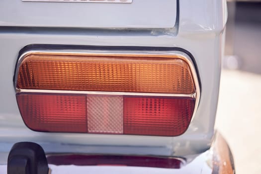 Close-up of a vintage car's tail light parked on a cobbled street, highlighting its classic aesthetic.