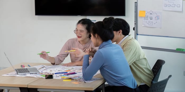 Team of UX developers and UI designers brainstorming ideas with sketches and laptops in a modern office setting.