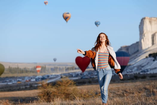 vibrant hot air balloons soar behind a stylish woman in striped shirt and jeans