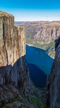 A picturesque view of the Kjeragbolten cliff in Norway, showcasing the majestic rock formations and the deep blue fjord below.