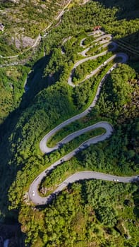 An aerial view of a scenic road winding through a lush green landscape in Norway.