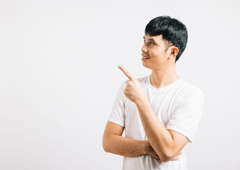 Smiling Asian man points his finger with enthusiasm, showcasing confidence and friendliness. Studio shot isolated on white background, perfect for highlighting your product or message.