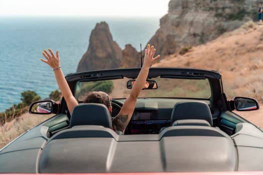 A woman is driving a convertible car on a mountain road, waving her hands in the air. Concept of freedom and excitement, as the woman enjoys the thrill of driving on the winding road