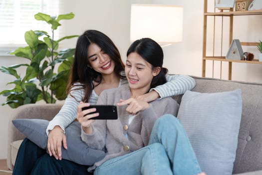 Happy woman lesbian gay lgbt couple enjoying fun gaming session on the couch at home.