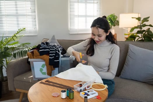 Woman recycling and upcycling clothes at home, showcasing sustainable living and environmental conservation efforts.