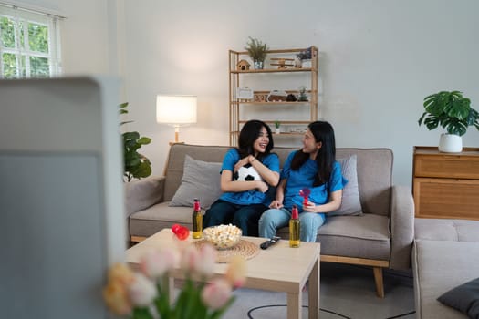 Excited emotional couple woman friends with soccer ball watching football game on tv.