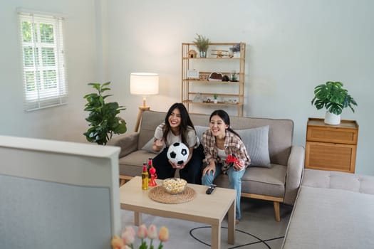 Excited emotional couple woman friends with soccer ball watching football game on tv.