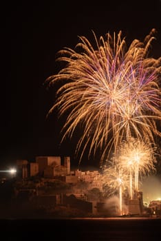 Embark on a visual journey as Peniscola's skyline becomes a canvas for a breathtaking fireworks display, meticulously captured through a telephoto lens, each explosion a testament to the city's vibrant energy and allure.