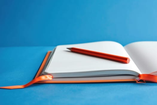 Open notebook with orange pen on blue background creativity and inspiration for business and travel planning