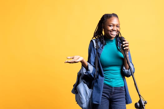 Upbeat african american singer holding microphone, performing tunes, isolated over yellow studio background. Energetic BIPOC musician singing to imaginary crowd, doing karaoke