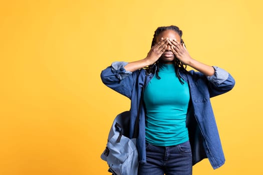 Tired BIPOC woman covering face with palms, exhausted after long day at work. African american person in need of break from job, obstructing eyes with hand, isolated over studio background