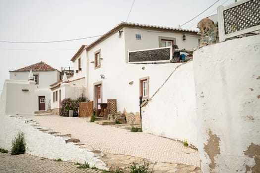 Exterior of beautiful white two-story houses in town. Typical empty street along white buildings in city. Residential buildings in Portugal city under clear sky.