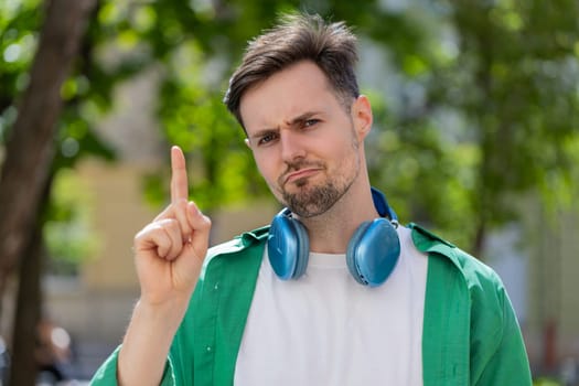 Displeased upset Caucasian man reacting to unpleasant awful idea, dissatisfied with bad quality, wave hand, shake head No, dismiss idea, don't like proposal. Young adult guy traveler on city street.