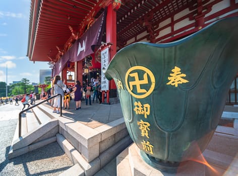 tokyo, asakusa - may 17 2024: Fireproof water tank in the shape of lotus petals adorned with a Buddhist manji swastika and inscriptions 'Devotion' 'In front of Buddha' on a side of the Sensoji temple.