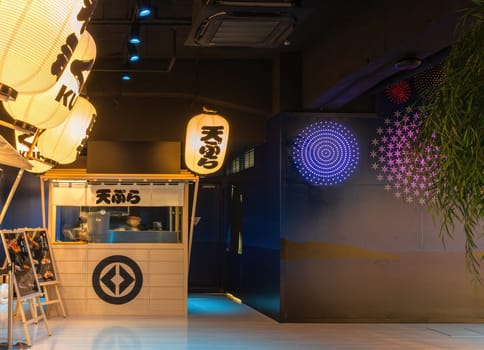 tokyo, japan - may 14 2024: Kura Revolving Sushi Bar Ginza interior with a traditional yatai stalls illuminated by paper lanterns and digital wall art figuring fireworks with a chef crafting tempura.