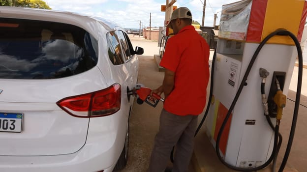 porto seguro, bahia, brazil - october 20, 2023: gas station attendant fills up gasoline and vehicle at a gas station