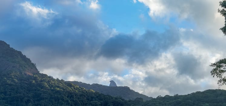 Majestic tropical mountains, dense forests, dramatic cloudy sky.